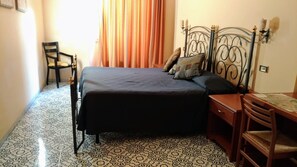 A bedroom with a bed, a chair, a wooden nightstand, and a map on the nightstand. - Nicolas Inn (Rome)