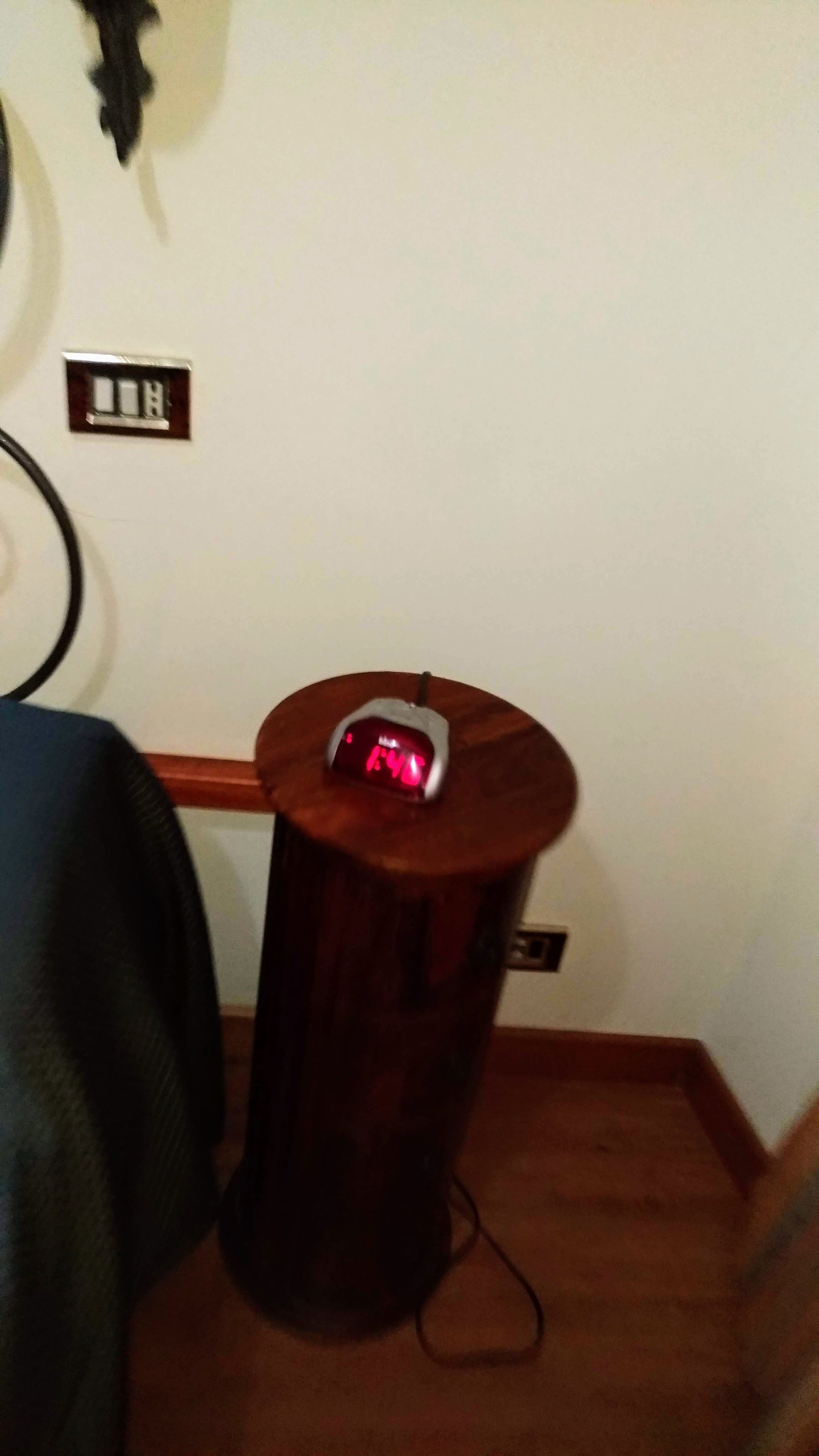 A wooden side table with a digital clock displaying 14:14.