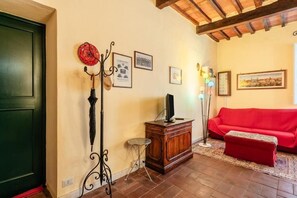 A living room with a red sofa, a wooden cabinet, and a floor lamp. - Tuscan style apartment in Centro Storico (Lucca)