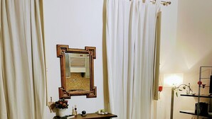 A bedroom with a bed, a dresser, a mirror, and curtains.