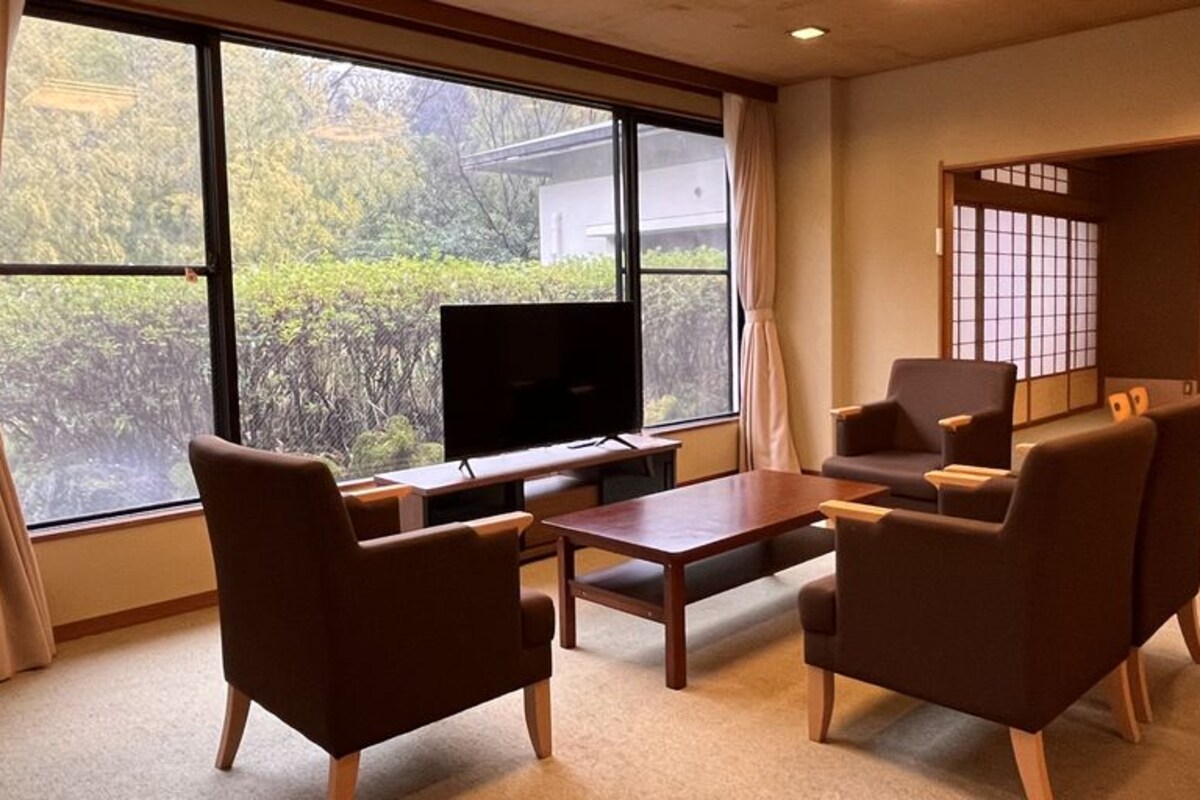Ein Zimmer mit Fernseher, Tisch und vier Stühlen.