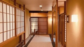 Un intérieur japonais traditionnel avec des portes coulissantes, un sol recouvert de tapis et un luminaire au plafond.