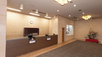 A reception area with a reception desk, a clock, a window, and a plant.