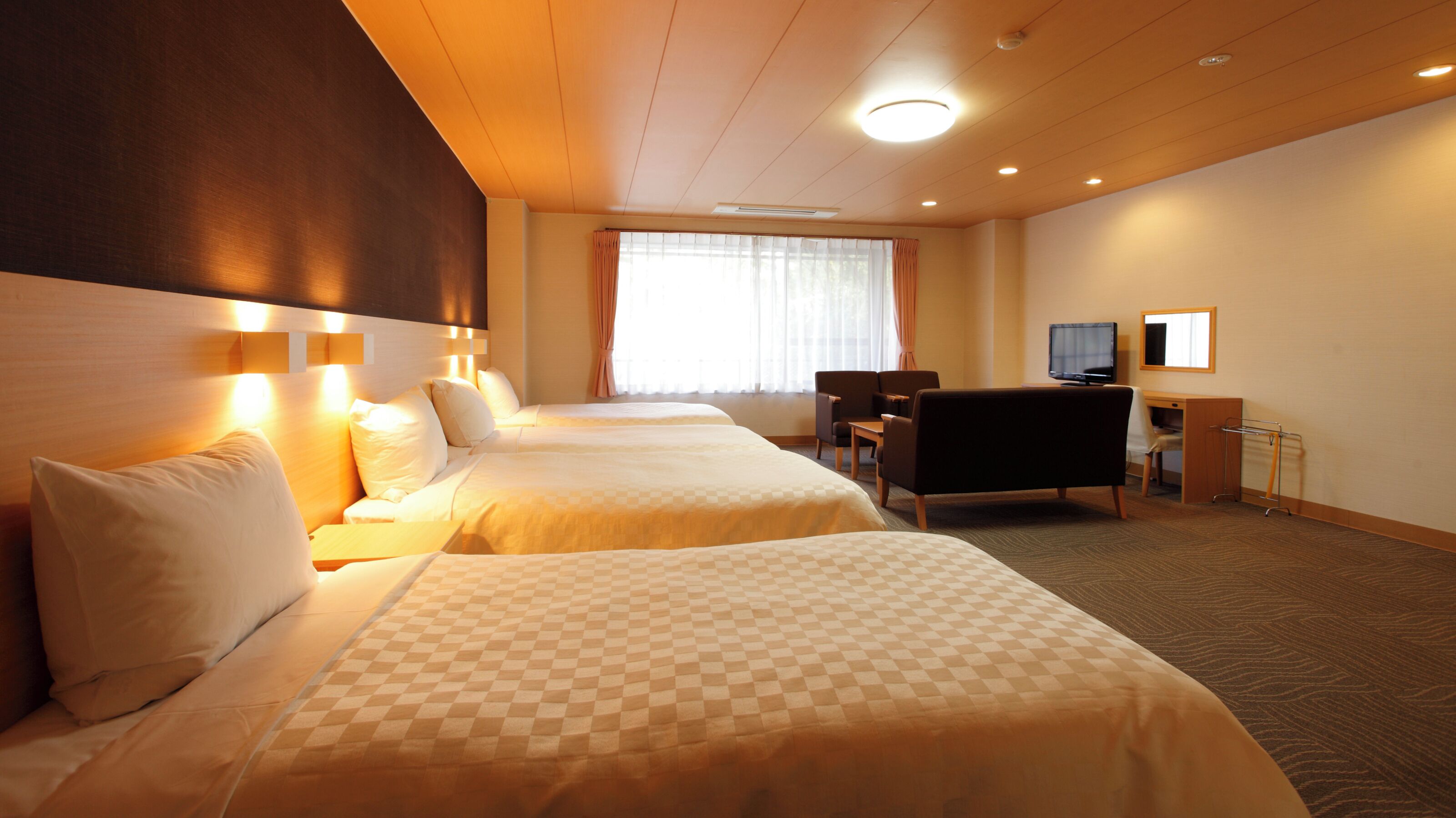 A hotel room with two beds, a desk, a chair, a television, and a window with curtains.