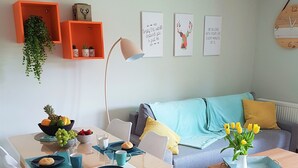 Ein modernes Wohnzimmer mit Essbereich, ausgestattet mit einem Holztisch, weißen Stühlen, einem Sofa und einem Couchtisch.