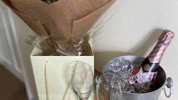 Un ramo de flores en papel de envolver, dos copas de vino vacías y una botella de champán en un balde de metal.