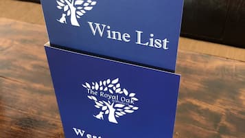 Two blue signs stacked on a wooden table, one labeled "The Royal Oak Wine List" and the other "Westcountry Gin & Tonic Menu".