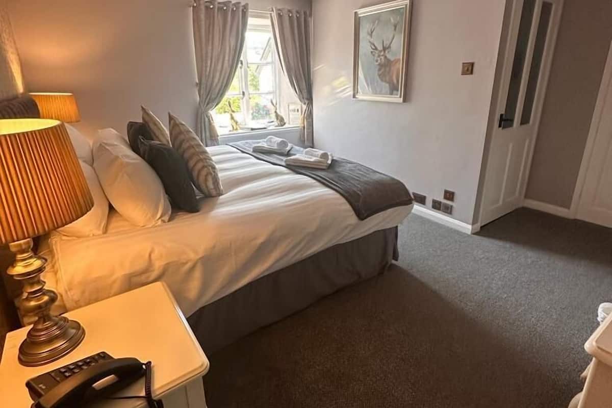 A bedroom with a bed, bedside table, lamp, and a painting on the wall.