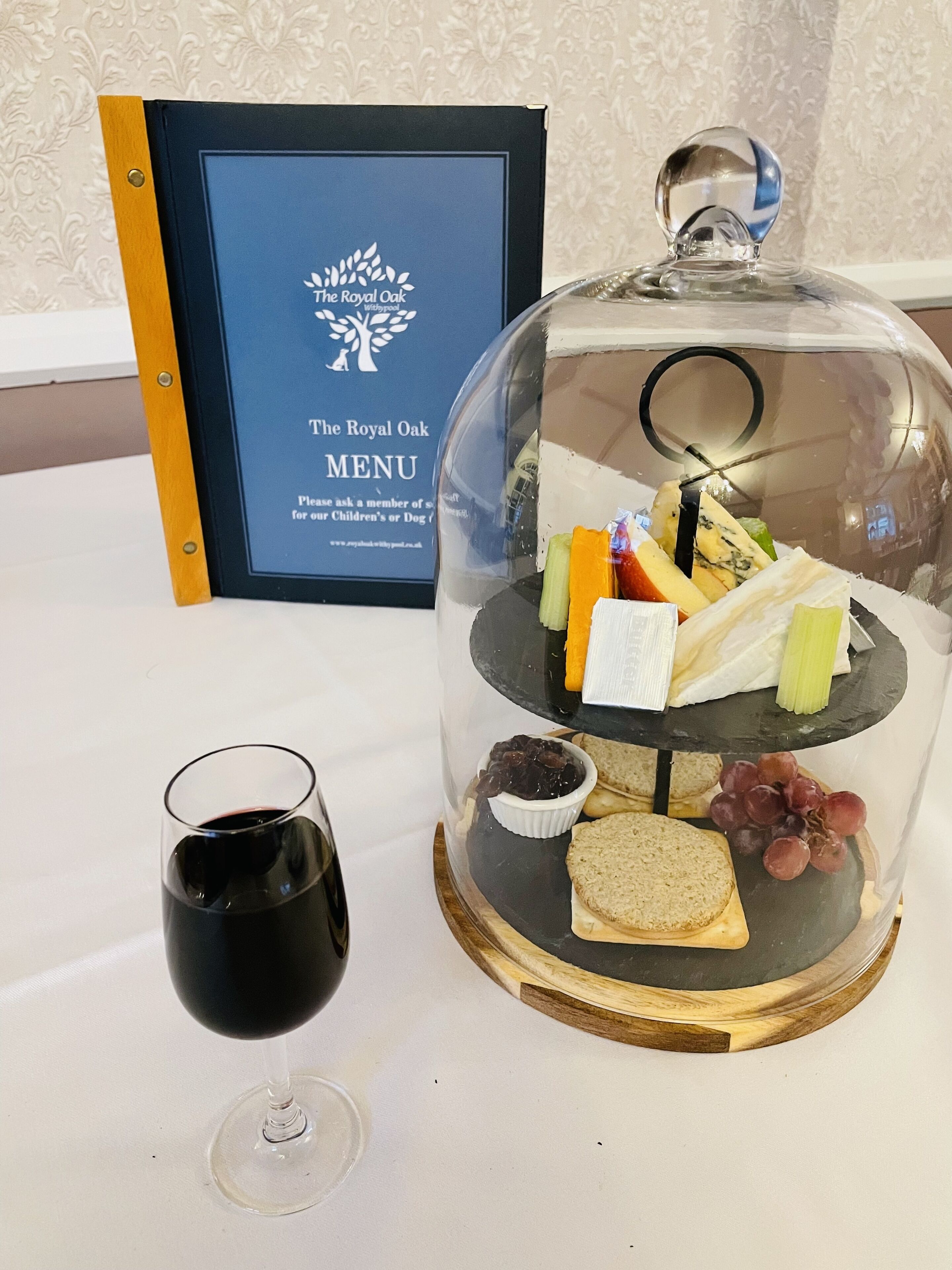 A food display with a glass dome, a wine glass, and a menu sign.
