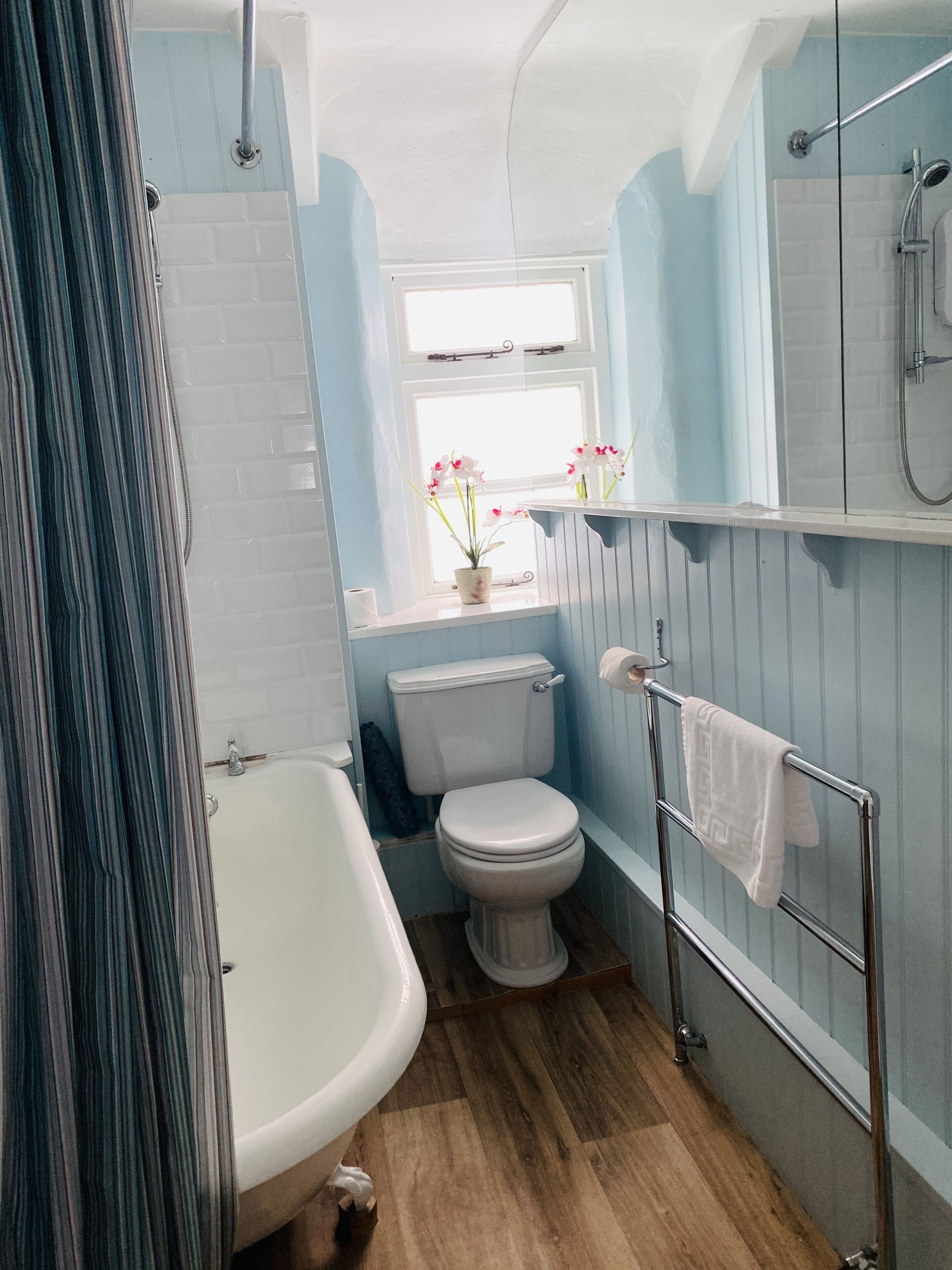 A bathroom with a white bathtub, a toilet, and a shower area.
