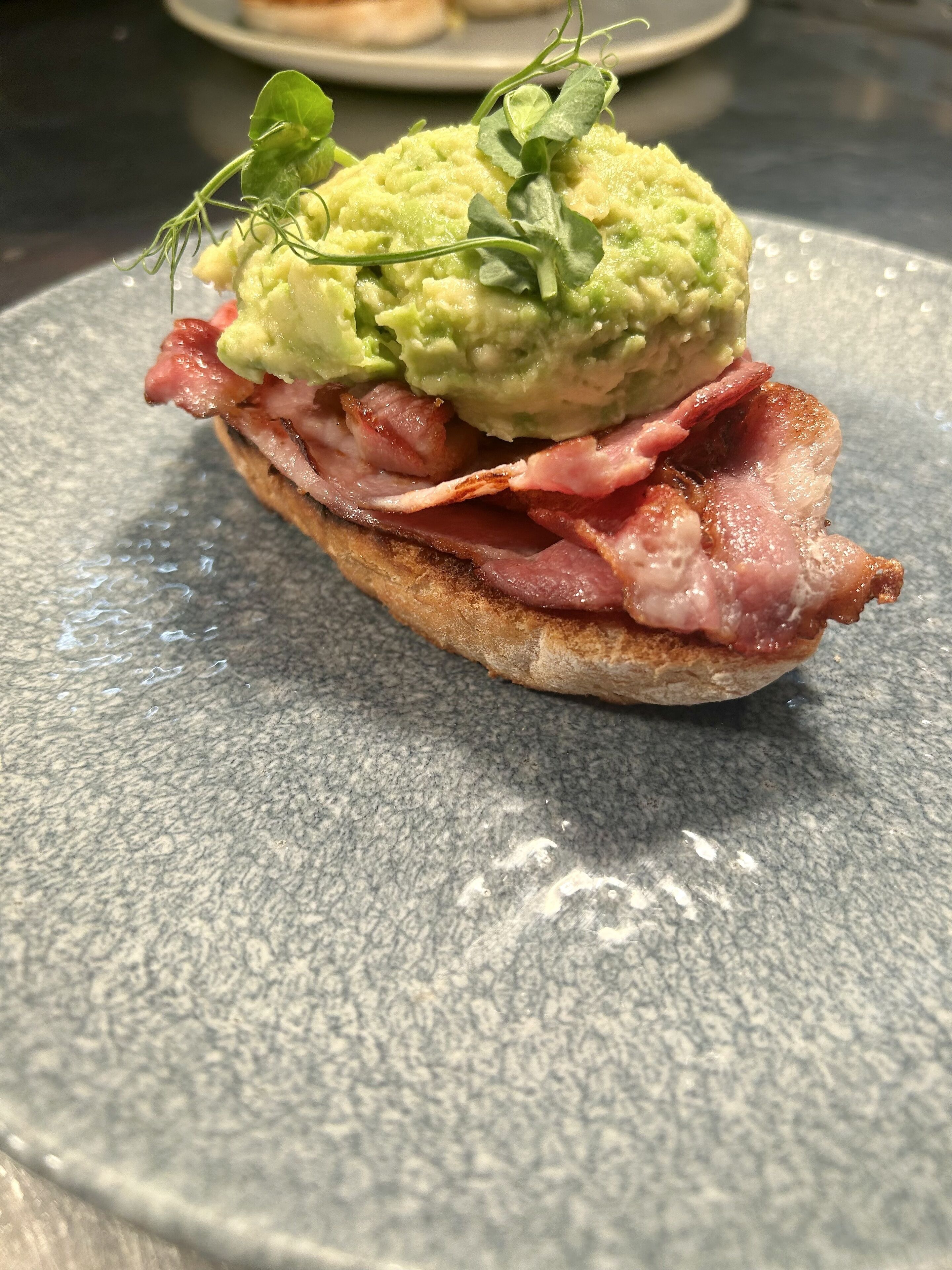 A sandwich with avocado and greens on a plate.