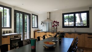 Una cocina moderna con ventanas amplias, una mesa de comedor con sillas y un florero con flores.