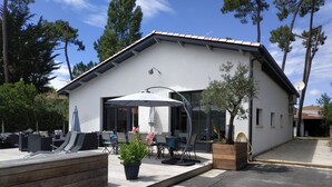 Una casa moderna con porche cubierto, mobiliario exterior y una planta en maceta.