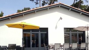 Un edificio con piscina, mobiliario exterior y un paraguas amarillo.
