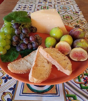 A plate with sliced bread, grapes, figs, and cheese on a patterned tablecloth. - B&B A Modo Mio Marsala (Marsala)