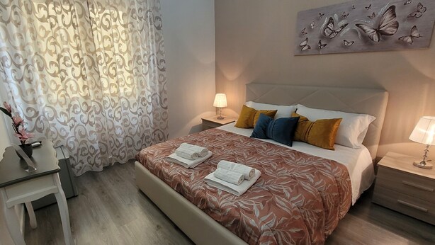 Un dormitorio ordenado con una cama, mesitas de noche y un buró.