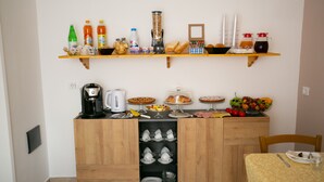 Une petite cuisine équipée d’une machine à café, d’un grille-pain et de divers produits alimentaires disposés sur le plan de travail.
