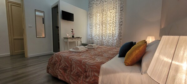 A hotel room with a bed, a desk, a TV, and a window with curtains. - B&B A Modo Mio Marsala (Marsala)