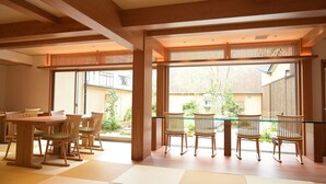 A dining area with wooden furniture and large windows.