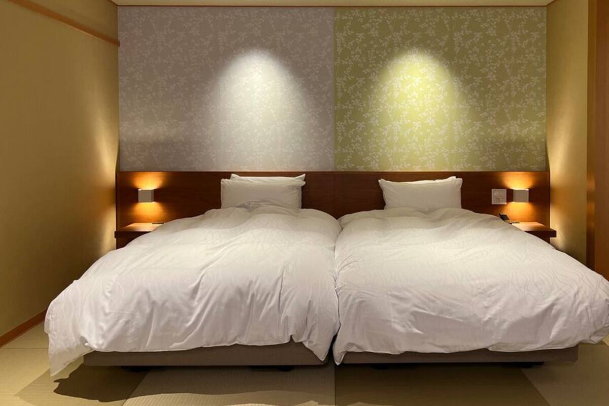 Ein Doppelbett mit zwei Nachttischen, einem Holz-Kopfteil und Wandleuchten.
