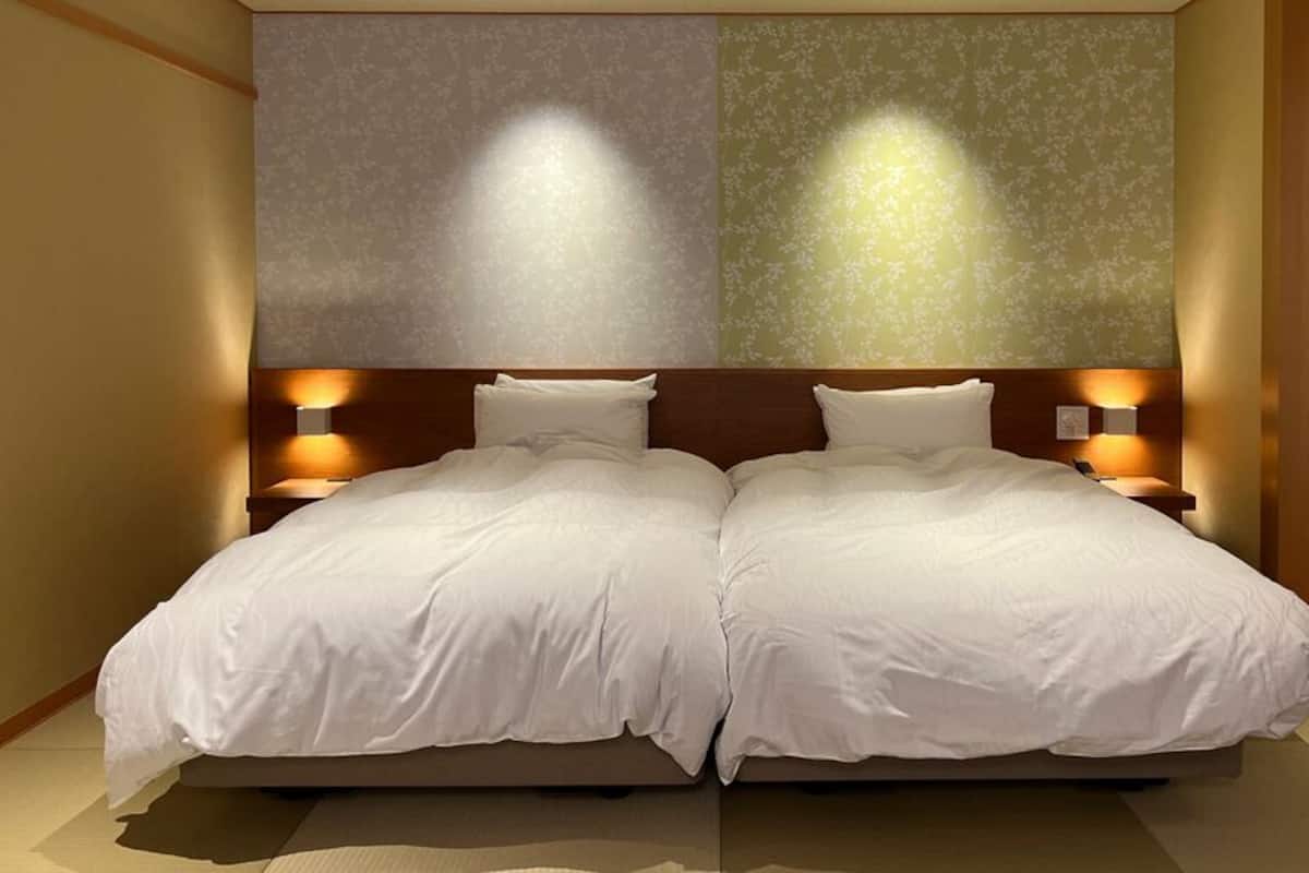 A double bed with two nightstands, a wooden headboard, and wall-mounted lamps.