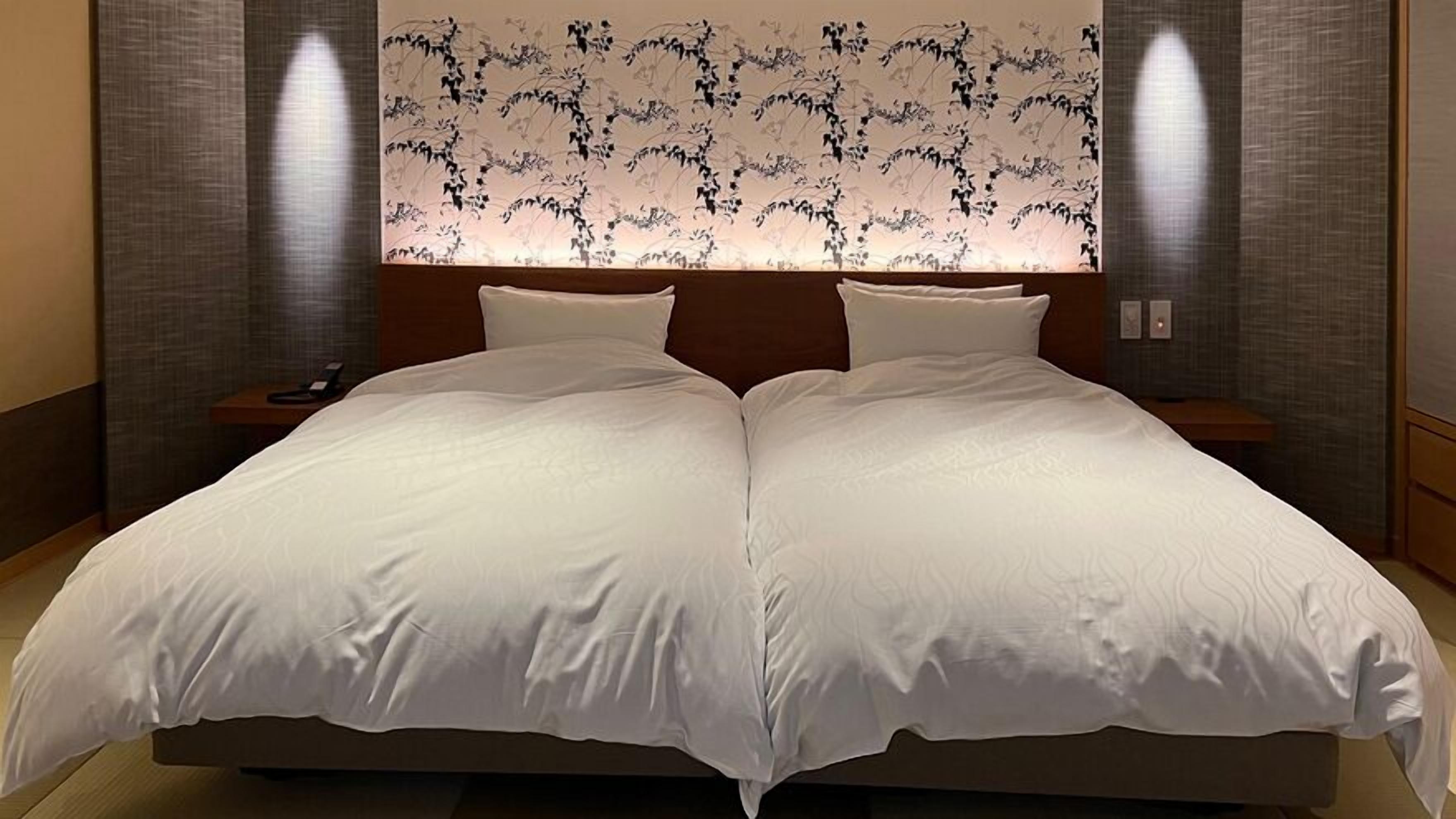 A double bed with white linens, a wooden headboard, and two bedside tables with lamps.