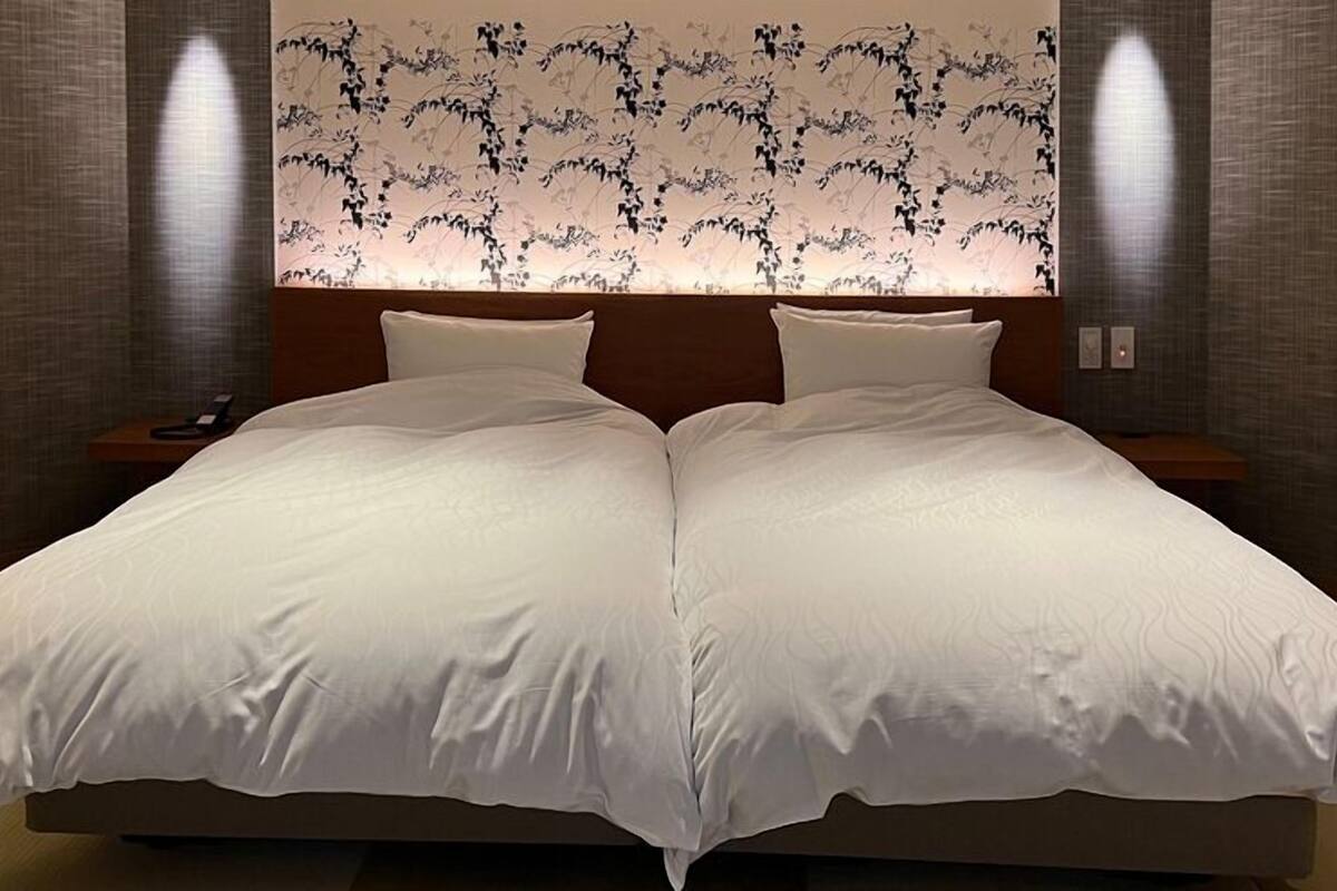 Ein Doppelbett mit weißer Bettwäsche, ein Holzkopfschild und zwei Nachttische mit Lampen.