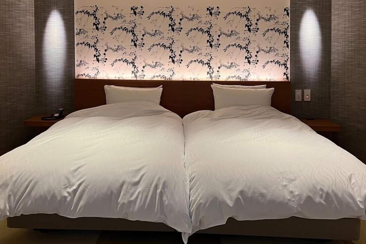 A double bed with white linens, a wooden headboard, and two bedside tables with lamps.