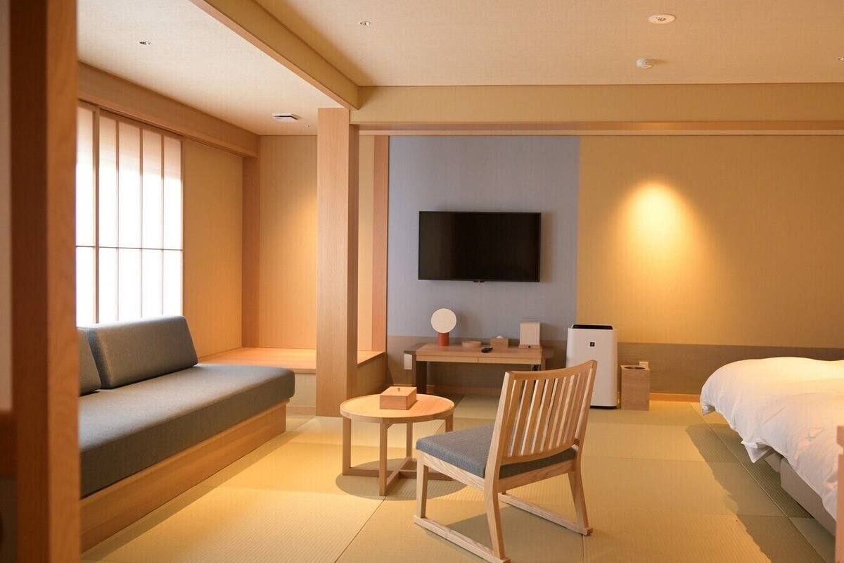 Ein Hotelzimmer mit einer Couch, einem Bett, einem Fernseher, einem kleinen Tisch und einem Sessel.