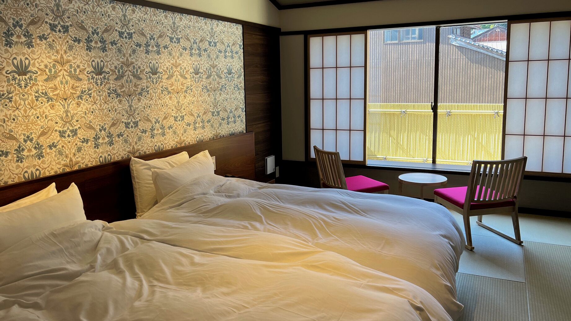 A hotel room with a large bed, a traditional Japanese sliding door, and a small table with chairs.