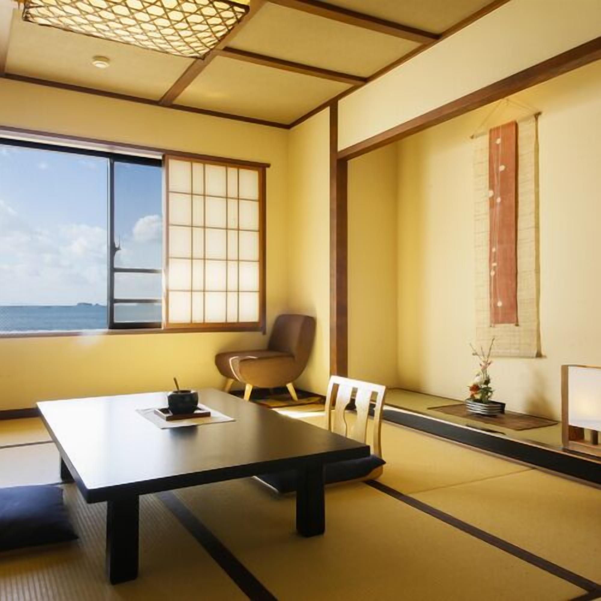 Une pièce de style japonais traditionnel, avec un sol recouvert de tatamis, une petite table sur laquelle est disposé un service à thé, une chaise et une fenêtre donnant sur la mer.