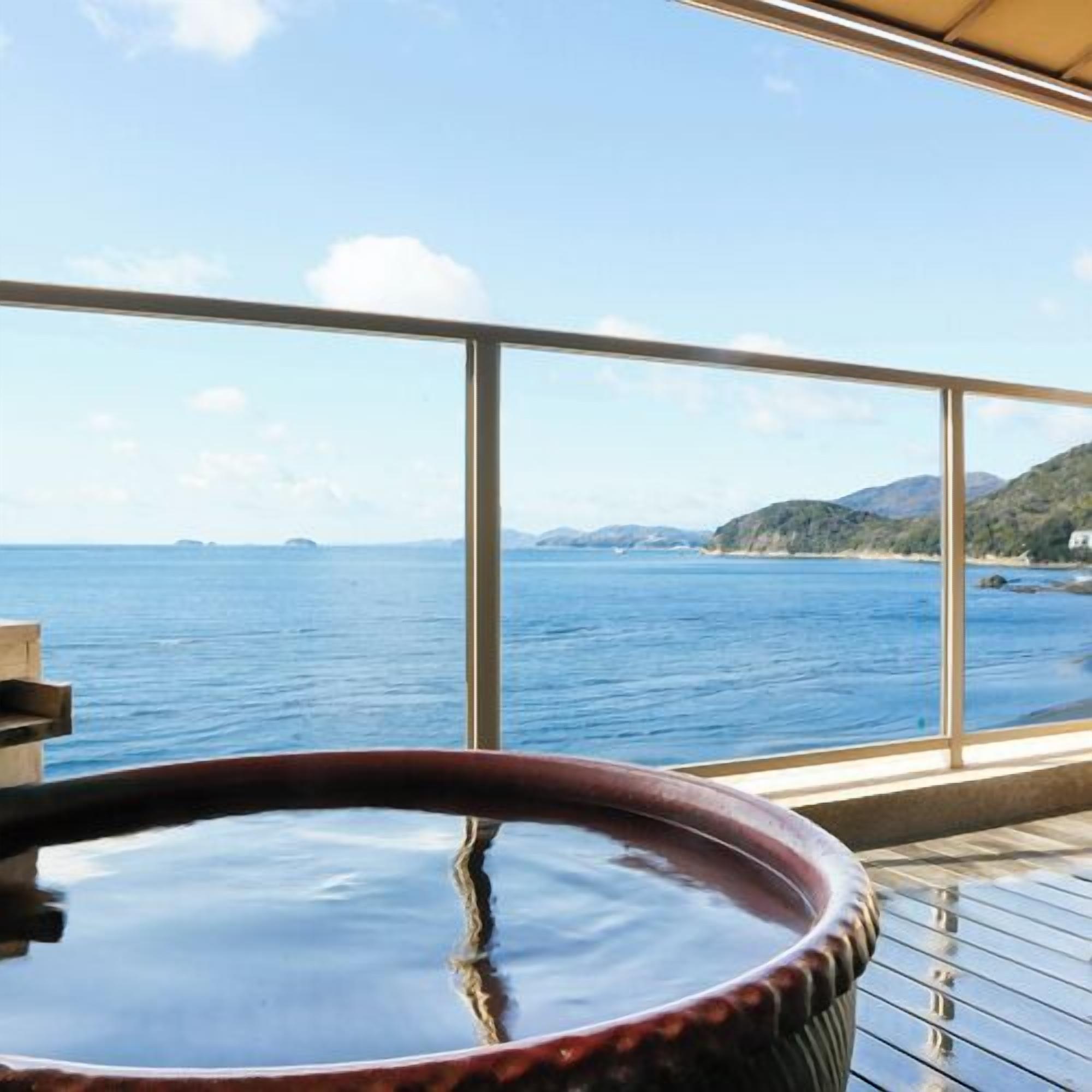 A hot tub with a view of the sea and distant hills.