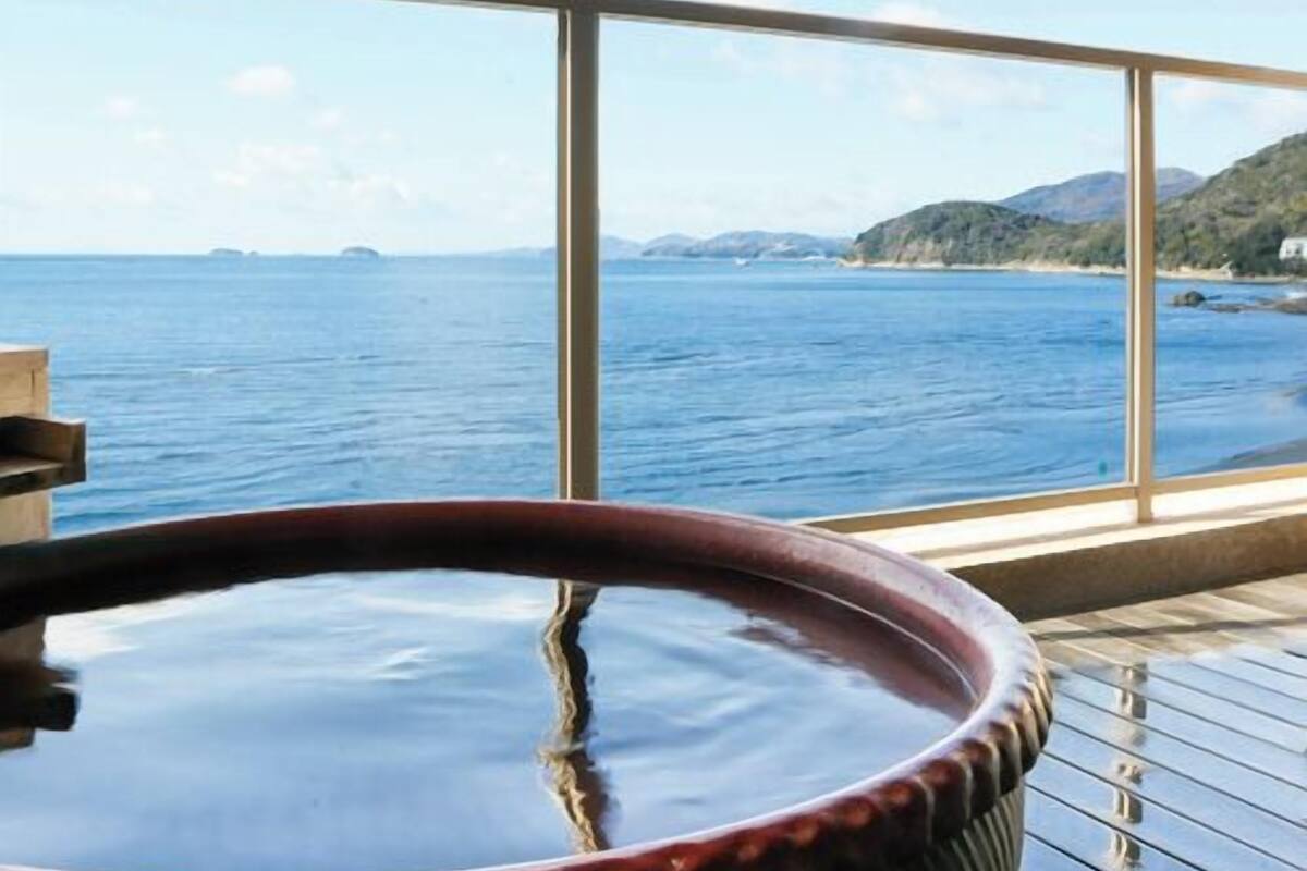 A hot tub with a view of the sea and distant hills.