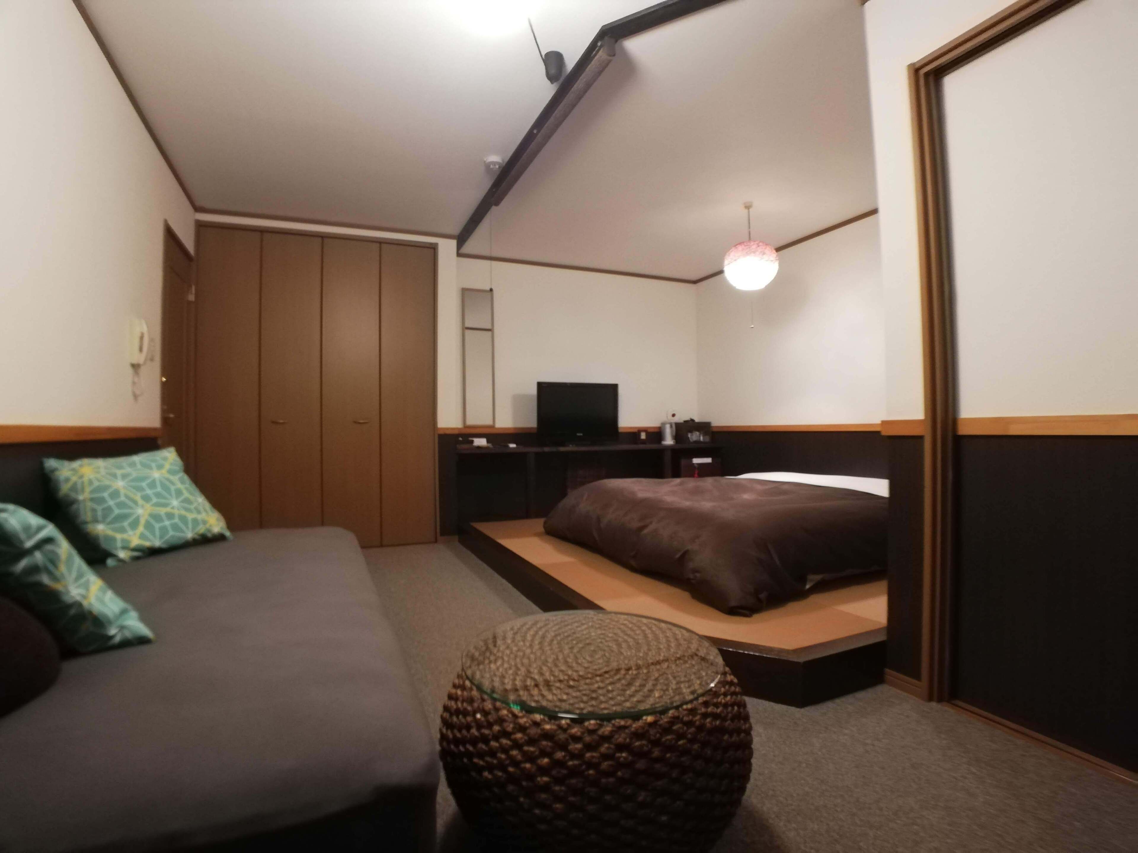 A bedroom with a bed, a sofa, a television, and a small round table.