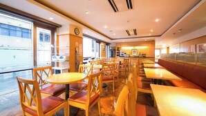 A restaurant with round tables and chairs, a counter, and a view of the outside. - Yokkaichi Urban Hotel (Yokkaichi)