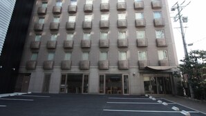 A multi-story hotel with a uniform facade, numerous windows, and a parking lot in front. - Yokkaichi Urban Hotel (Yokkaichi)