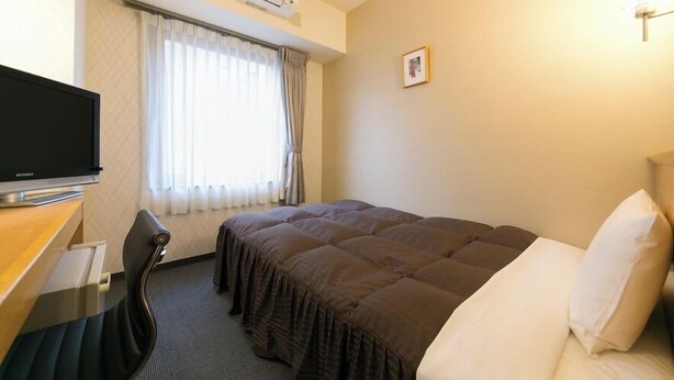 A hotel room with a bed, a desk with a chair, a television, and a window with curtains. - Yokkaichi Urban Hotel (Yokkaichi)