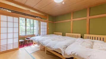A traditional Japanese-style room with tatami flooring, a futon bed, sliding shoji doors, and a view of greenery outside.