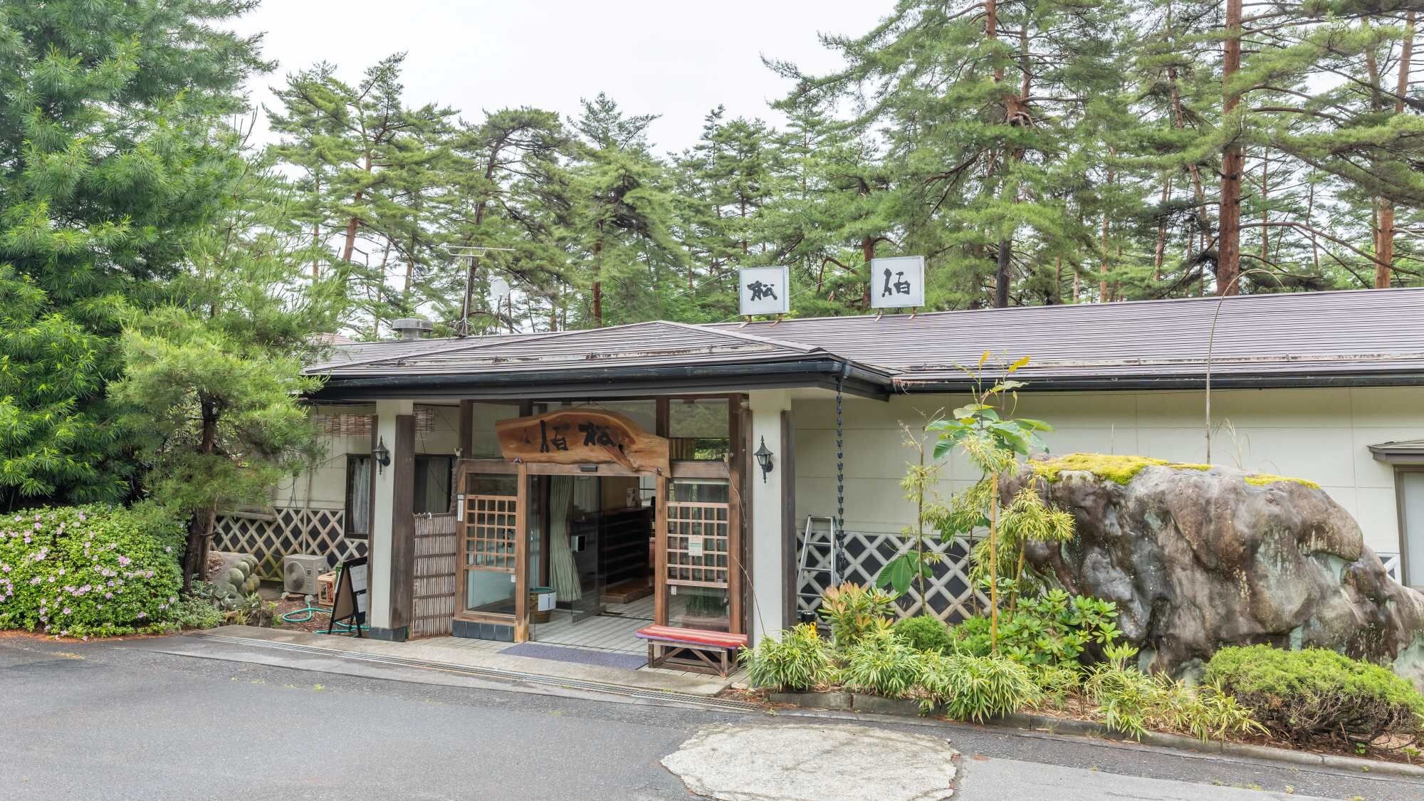 A traditional Japanese building with a wooden entrance and a signboard.