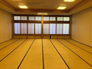 Ein Zimmer mit Tatami-Böden, Schiebetüren und einem großen Fenster mit Ausblick.