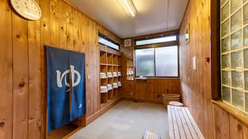 A wooden interior with a clock, a towel rack, a bench, and a window with frosted glass.