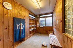 A wooden interior with a clock, a towel rack, a bench, and a window with frosted glass.