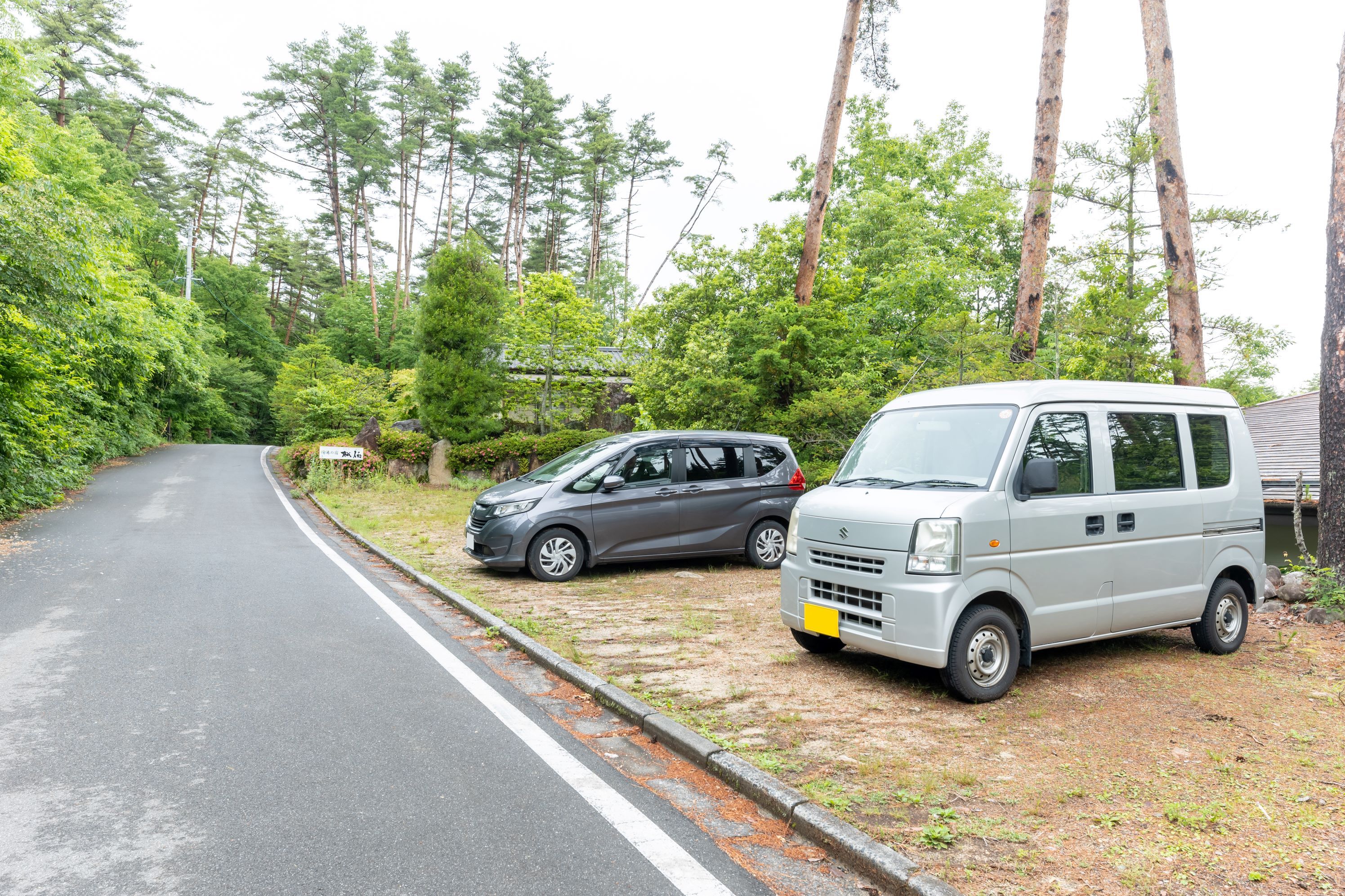 A road with two parked vehicles, a car and a van, on the side.