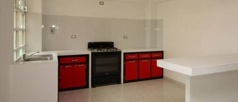 A kitchen with white cabinets, a black stove, and red lower cabinets.