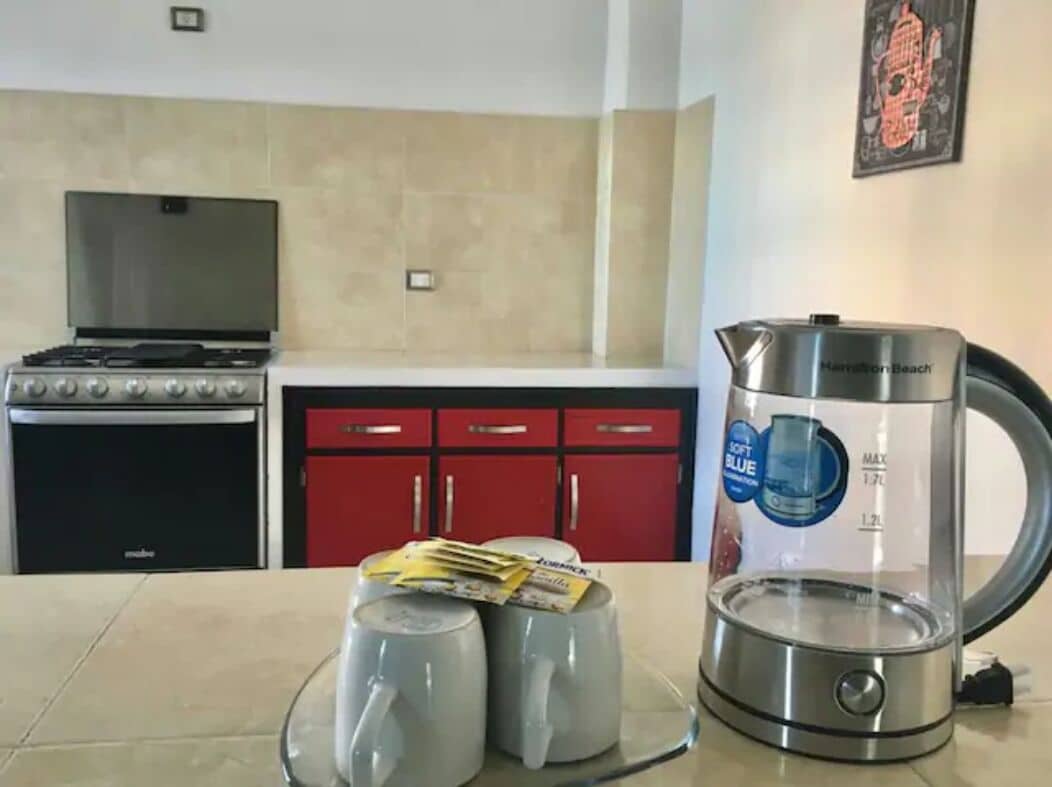 Une cuisine équipée d’une cuisinière à gaz, d’une machine à café et de deux tasses posées sur le comptoir.