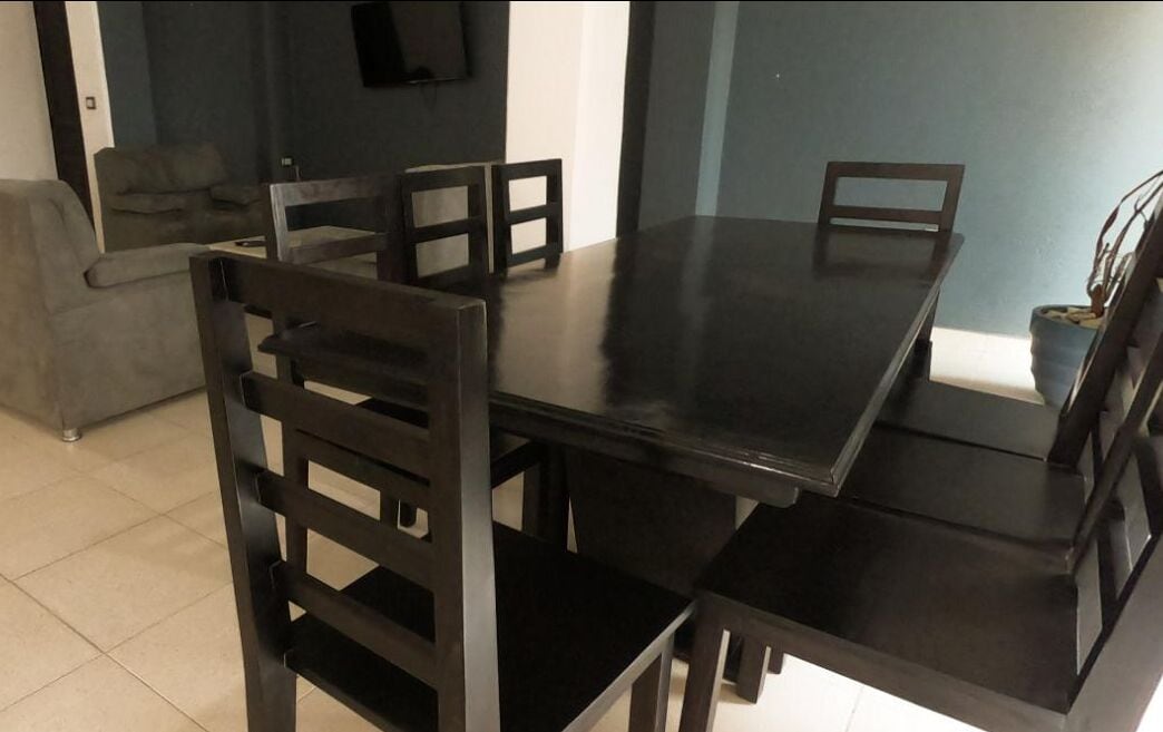 Comedor con una mesa y sillas a juego en madera oscura.