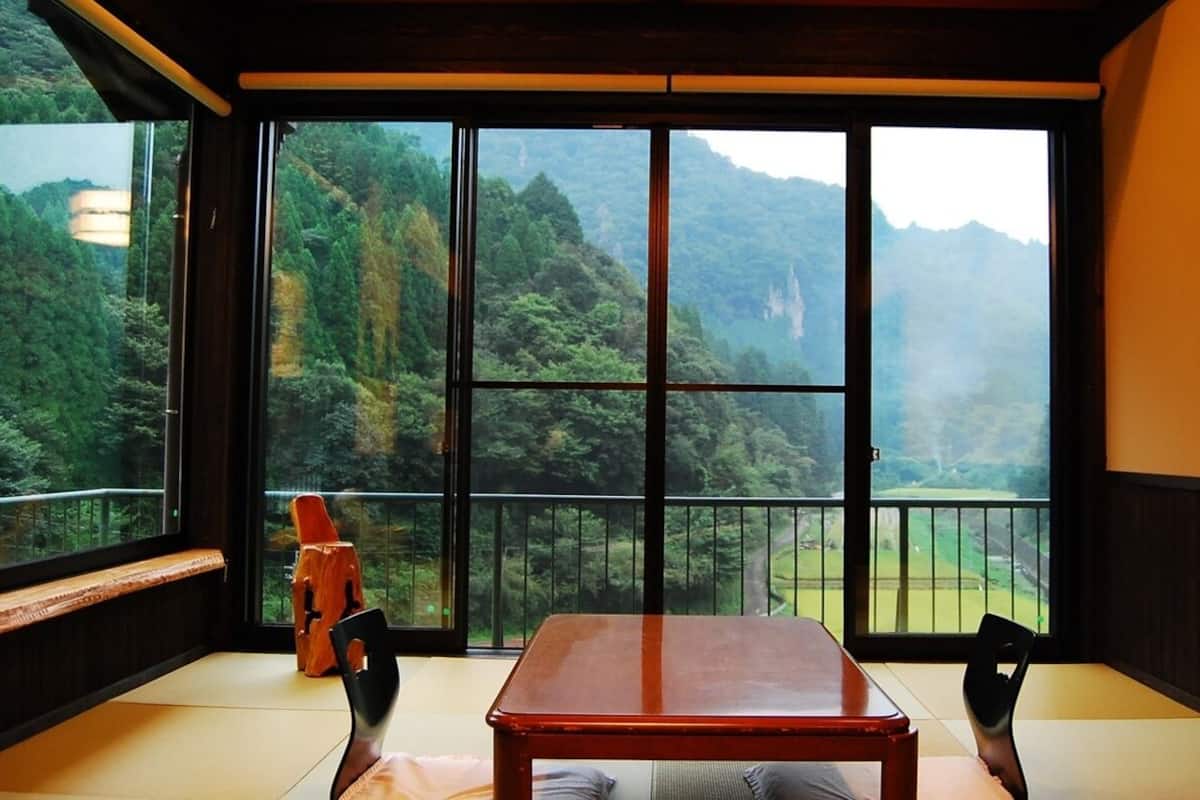 A room with a large window, a wooden table, and a chair.