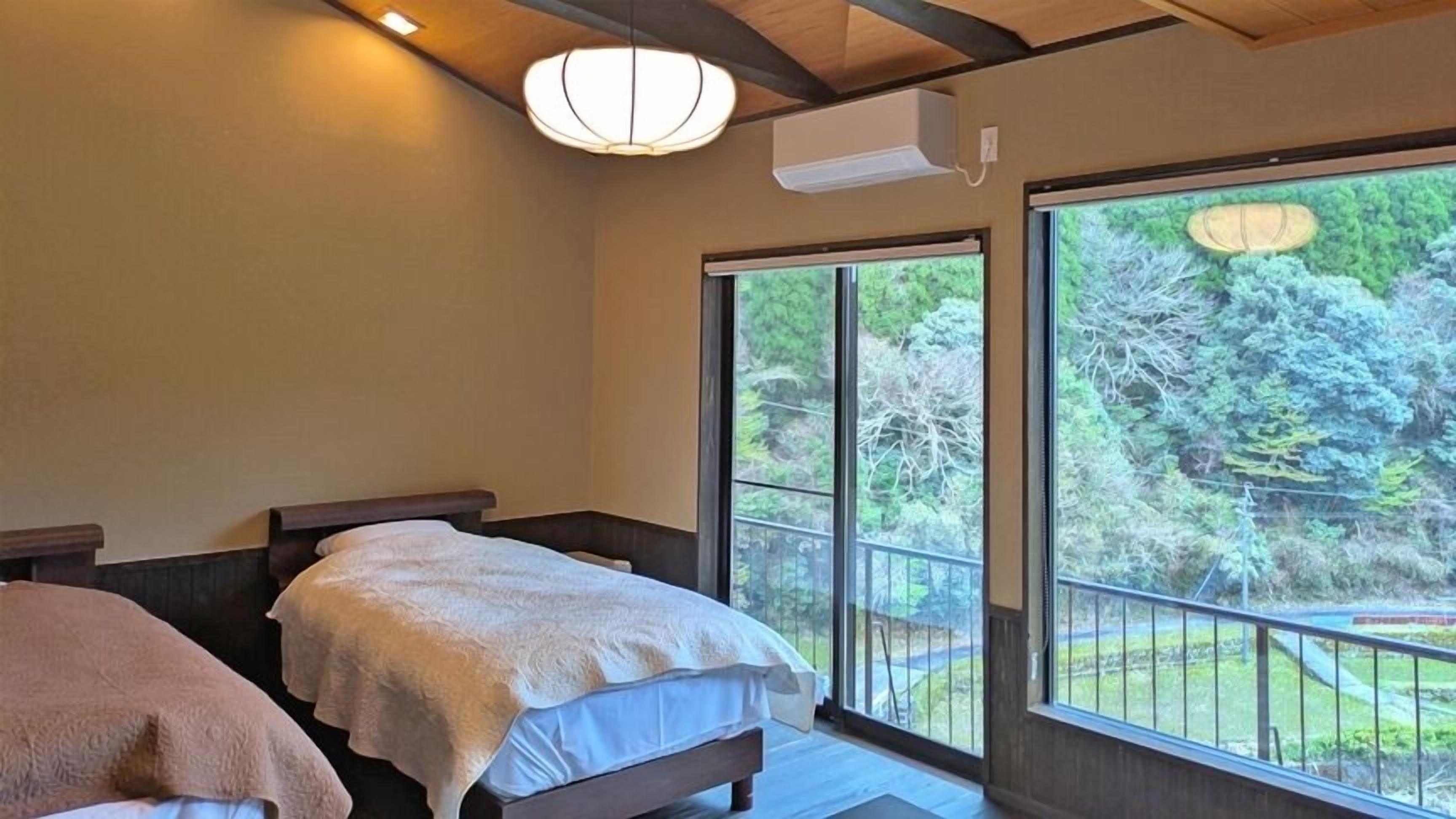 Una camera da letto con due letti, un'ampia finestra e una ventola a soffitto.