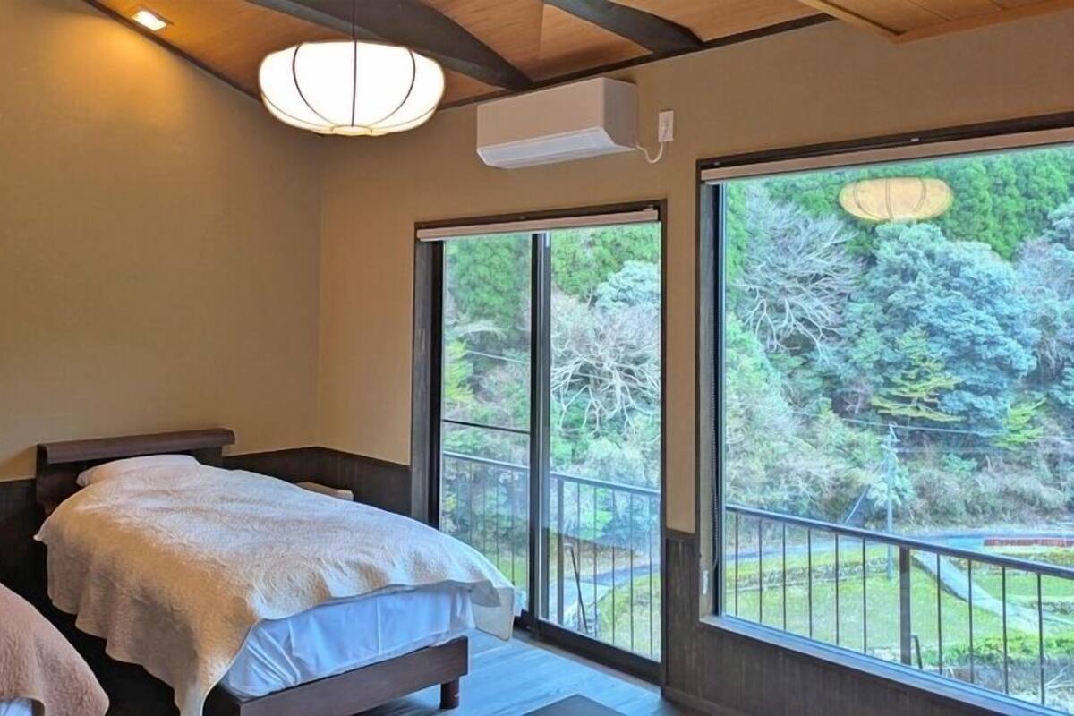 A bedroom with two beds, a large window, and a ceiling fan.