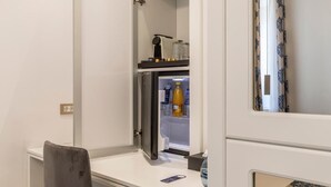 Une petite cuisine équipée comprenant un réfrigérateur intégré, un petit plan de travail et une chaise.
